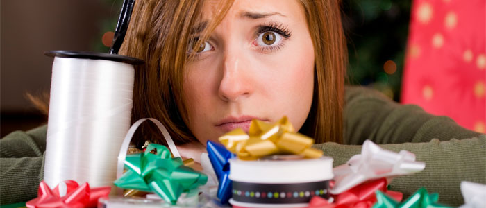 A stressed woman looking over a table covered in gift wrapping